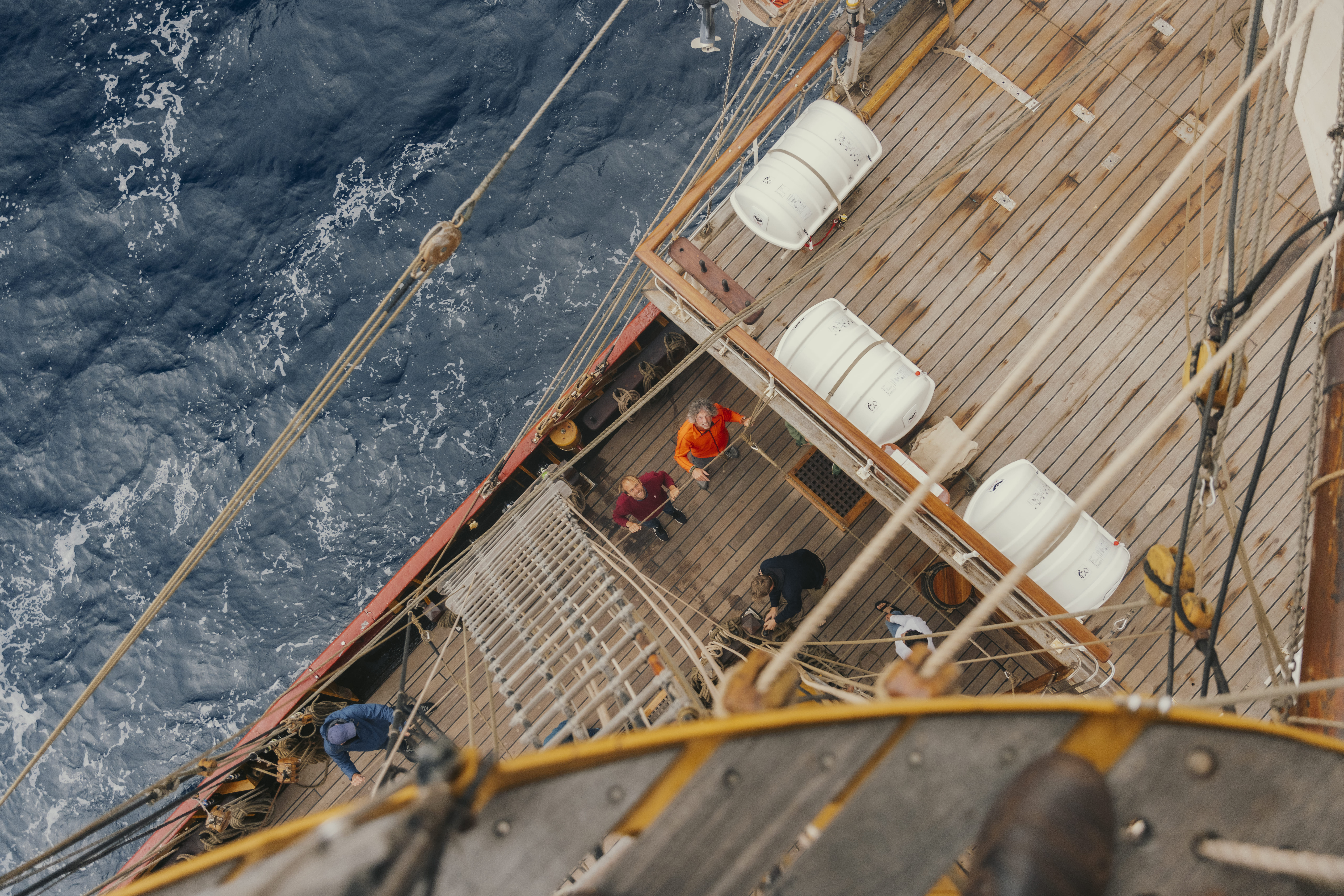 Looking down from the mast — crew on deck, ocean below